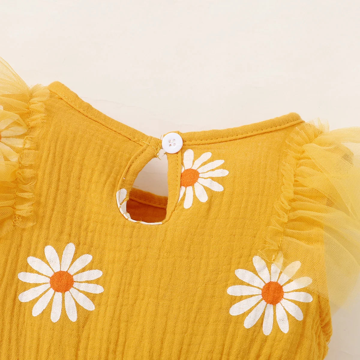 Cute summer dress for baby girls with cheerful daisy pattern featuring it's button